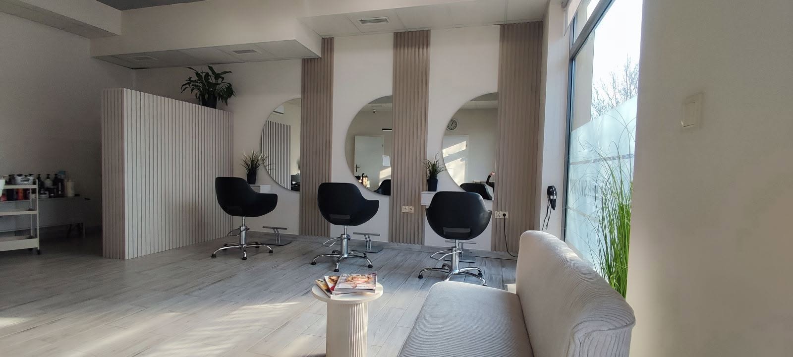 Jasne wnętrze salonu z łukowymi lustrami i czarnymi fotelami